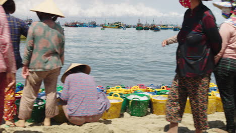 Toma-De-Seguimiento-De-Pescadores-Ocupados-Clasificando-Cestas-De-Pescado-Fresco,-Playa-De-Mui-Ne