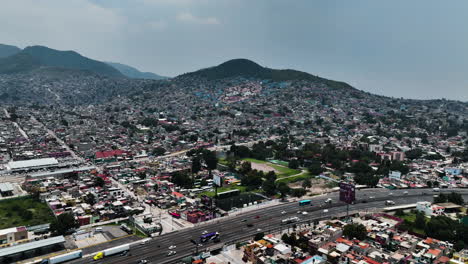 Aerial-view-over-a-road-approaching-a-face-in-the-hills-of-Ecatepec-de-Morelos,-Mexico