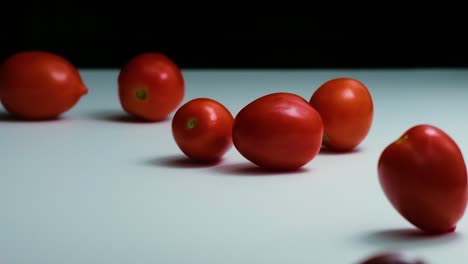 Essen-In-Zeitlupe:-Eine-Große-Menge-Tomaten-Purzelt-Auf-Eine-Schwarz-weiß-Verspiegelte-Oberfläche,-Hüpft-Und-Rollt-In-Einer-Spielerischen,-Faszinierenden-Bewegung-Zurück