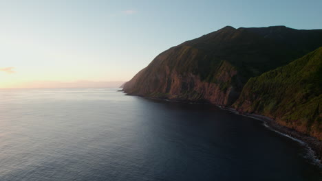 Aerial-panoramic-view-of-coastal-cliffs-illuminated-by-setting-sun