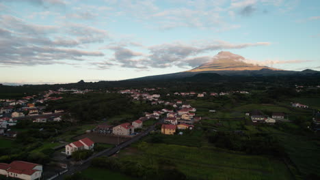 Aufsteigende-Luftaufnahmen-Von-Wohnhäusern-In-Der-Stadt-Und-Dem-Majestätischen-Berg-Ponta-Do-Pico-Im-Hintergrund