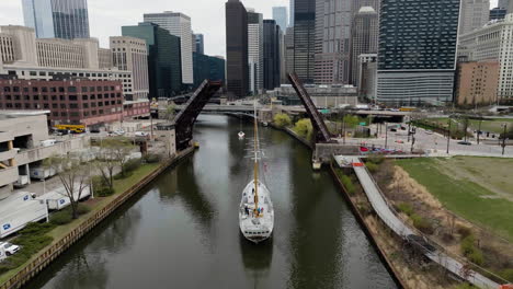 Drone-shot-following-the-tall-ship-Windy-driving-under-a-open-bridge-on-the-Chicago-river,-spring-in-USA