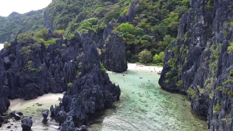 Aerial-wide-view-of-tropical-shallow-azure-clear-water-lagoon-between-karst-rock-cliffs