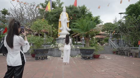 Turistas-Tomando-Fotos-De-Una-Mujer-Rezando-Ante-La-Estatua-Blanca-De-La-Deidad-Quan-Am-En-La-Pagoda-Van-Son-En-Con-Dao,-Vietnam