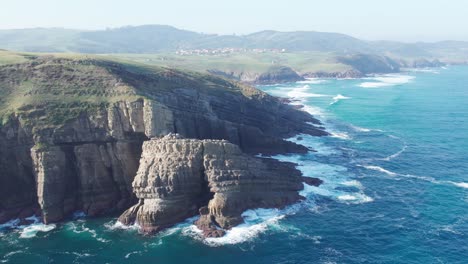 Dunstige-Küste,-Luftaufnahme-Von-Wellen,-Die-In-Die-Verträumte-Küste-Von-Playa-De-Tagle,-Spanien,-Krachen
