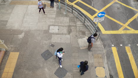 Top-down-view-of-people-waiting-at-crosswalk-on-concrete-sidewalk-in-asia