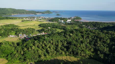 Panoramic-view-of-an-oceanfront-village-community-and-lush-jungle-rainforest-in-Baras,-Catanduanes,-Philippines