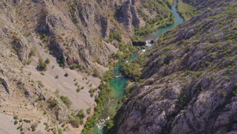 Wide-shot-of-kayaks-cruising-in-Zrmanja-river-turquoise-blue-water,-aerial