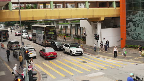 Vista-Estática-De-Una-Calle-Muy-Transitada-En-Hong-Kong-Con-Coches,-Autobuses-Y-Gente-Que-Viaja.