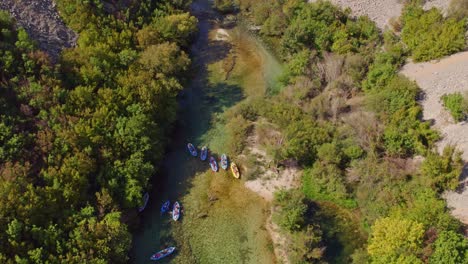 Blue-and-yellow-kayaks-floating-in-crystal-clear-Zrmanja-river-Croatia,-aerial