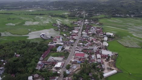 Reveal-shot-of-small-village-next-to-road-at-Sumba-island-Indonesia,-aerial