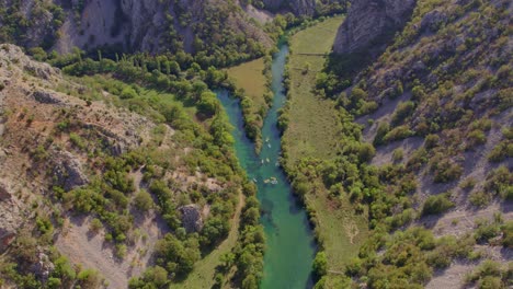 Panoramic-shot-of-people-kayaking-in-zrmanja-river-during-daytime,-aerial