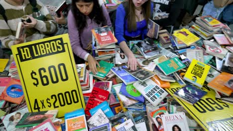 Panorámica-En-ángulo-De-Arriba-Hacia-Abajo-Sobre-Manos-Ocupadas-Agarrando-Libros-De-La-Mesa.