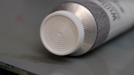 Pan-across-white-plastic-cover-on-oil-painting-tube