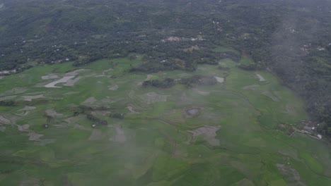 Wide-shot-of-lush-green-rice-paddies-with-low-clouds-at-Sumba-island,-aerial