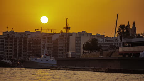 Sliema-harbor-in-Malta-at-sunset,-the-sun-going-down-with-golden-sky