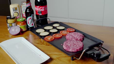 Medium-shot-of-hand-putting-mouthwatering-burgers-on-electric-plancha-grill