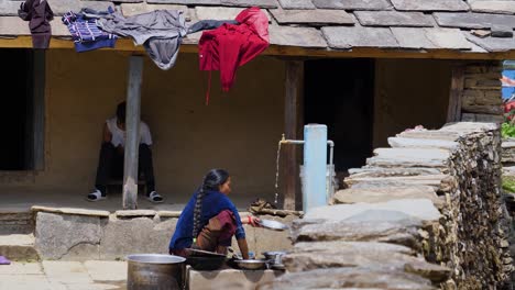 Nepalese-or-tibetan-woman-washes-silver-dishes-and-pans-at-neighborhood-fountain