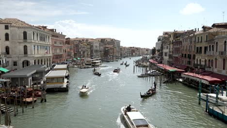Una-Vista-Cinematográfica-Del-Gran-Canal-Desde-El-Puente-De-Rialto-En-Venecia,-Donde-Los-Barcos-Se-Mueven-Por-El-Canal