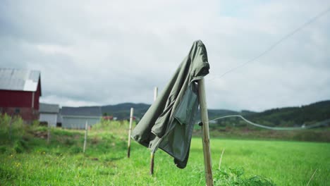 Hooded-Jacket-Hanging-On-Fence-Post,-Blown-By-The-Wind-At-The-Field