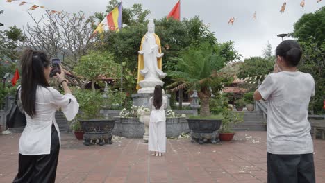 Un-Turista-Tomando-Fotos-De-La-Estatua-Blanca-De-La-Deidad-Quan-Am-En-La-Pagoda-Van-Son-En-Con-Dao,-Vietnam