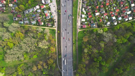 Top-down-aerial-drone-view-of-large-traffic-on-highway-road-in-Vienna,-tilt-up-reveals-bridge