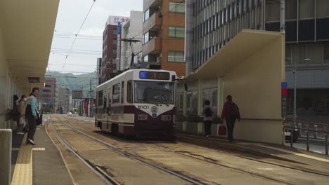 Tranvía-Esperando-En-La-Plataforma-Para-Que-Los-Viajeros-Embarquen-En-Hakodate,-Hokkaido