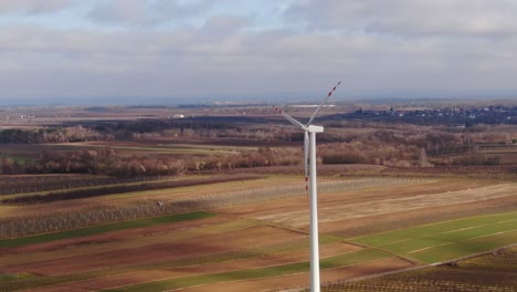Luftparallaxe-Einer-Windkraftanlage-Inmitten-Landwirtschaftlicher-Felder-Mit-Wolkenschatten-Auf-Bäumen