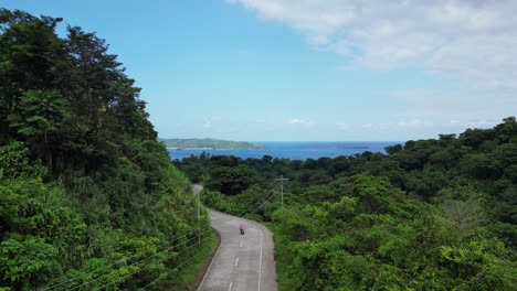 Rising-drone-shot-of-hillside-road-overlooking-stunning-tropical-island-mountains-and-skyline-in-Baras,-Catanduanes
