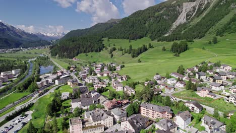 Drone-above-green-valley-and-town-of-Samedan,-Switzerland