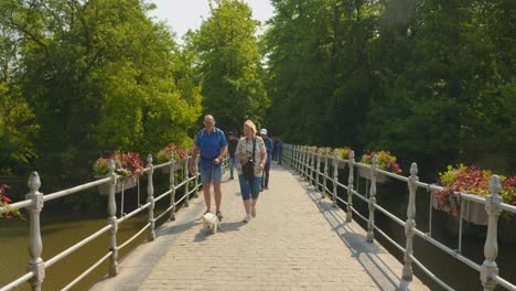 Aged-Couple-Strolling-With-Dog-Pet-At-Minnewater-Park-In-Bruges,-Belgium