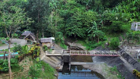 Idyllic-aerial-dolly-of-tropical-jungle-and-river-park,-and-metal-bridge-in-Catanduanes,-Philippines
