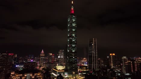 Vuelo-Aéreo-Hacia-La-Gigantesca-Torre-101-Y-El-Horizonte-De-La-Ciudad-De-Taipei-Por-La-Noche
