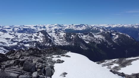 Riesige-Schneebedeckte-Berglandschaft-Mit-Tiefen-Tälern-Vom-Gipfel-Aus---Schiebender-Drohnenschuss