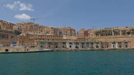 View-of-towering-cityscape-port-town-walls-of-valletta-malta-from-boat-in-water