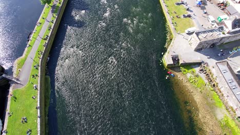 People-at-Claddagh-in-Galway-near-Corrib-River-on-sunny-day,-picnic-and-kayaking