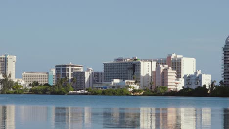 Condado-Lagoon-panoramic-view-with-Hilton-hotels,-resorts-and-Puente-Dos-Hermanos-of-the-area-in-the-background---Pan-left