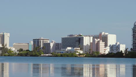 Vista-Panorámica-De-La-Laguna-Del-Condado-Con-Los-Hoteles-Hilton,-Resorts-Y-El-Puente-Dos-Hermanos-Del-área-Al-Fondo---Panorámica-Hacia-La-Izquierda