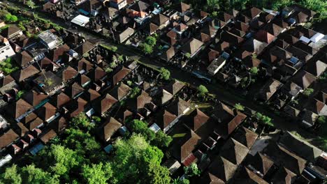 Aerial-drone-camera-flying-over-a-residential-building-in-Ubud-Bali,-Indonesia-with-a-road-running-through-the-middle-and-many-vehicles-driving-on-it,-a-night-scene