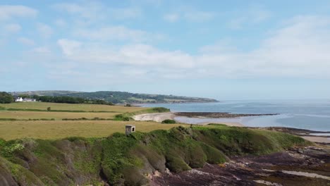 Traeth-Lligwy-crumbling-shoreline-aerial-view-pull-back-establishing-scenic-green-Welsh-weathered-coastline