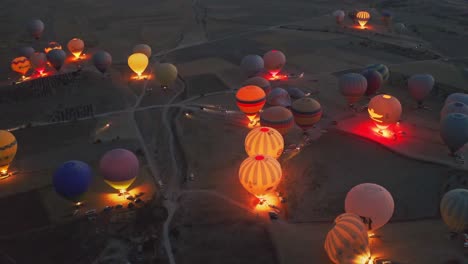 established-shot-with-people-doing-hot-air-balloon-tour-at-night-over-the-valley-in-Cappadocia-Turkey,-this-place-is-best-for-tourists-and-enjoy-amazing-adventure,-aerial-drone-camera-is-going-above