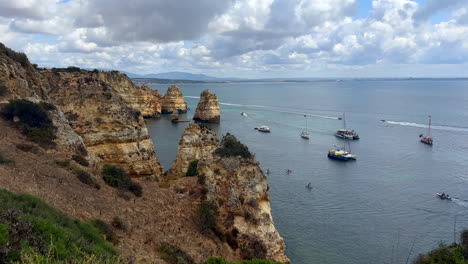 Weitwinkelaufnahme-Der-Algarve-Küste-Mit-Parkenden-Booten-Und-Schiffen-Mit-Touristen-An-Bewölkten-Tagen-In-Lagos,-Portugal