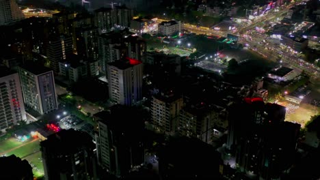 established-aerial-shot-of-urban-cityscape-of-Surat-city,-high-rise-and-low-rise-building-at-night,-vehicle-passing-on-road-at-night