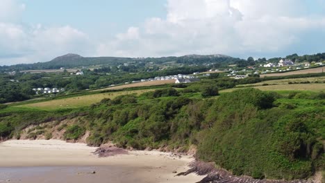 Panning-across-Traeth-Lligwy-Anglesey-hillside-farmland-aerial-view-overlooking-Welsh-weathered-coastline