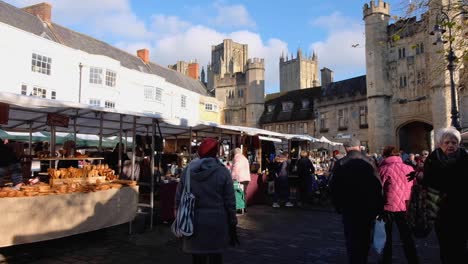 La-Gente-De-Compras-Y-Deambulando-Por-Los-Puestos-De-Vendedores-En-El-Concurrido-Mercado-De-La-Ciudad-De-Wells,-Somerset,-Inglaterra