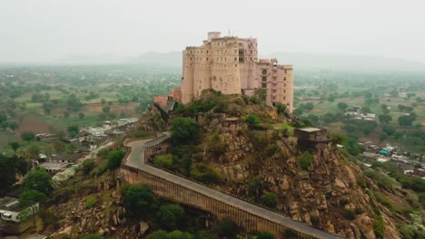 established-shot-of-Aerial-drone-camera-zooming-over-Leela-Bisangarh-Jaipur-fort-showing-a-very-old-fort-built-on-a-mountain-hill