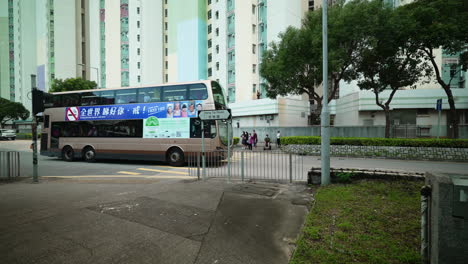 People-waiting-patiently-at-crosswalk-as-double-decker-bus-rounds-the-corner-in-hong-kong