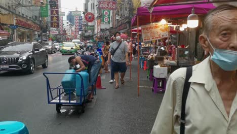 Un-Anciano-Caminando-Lentamente-Por-La-Calle-Principal-De-Chinatown-En-Bangkok-Con-Puestos-De-Comida