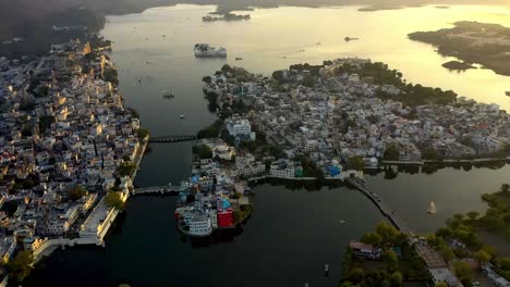 established-shot-of-Udaipur-city,-an-Aerial-drone-camera-flying-over-Udaipur-city-in-which-the-rotating-core-of-the-city-is-water,-incredible-India,-sunset-is-also-happening-later