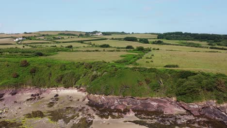 Traeth-Lligwy-Anglesey-eroded-coastal-shoreline-aerial-view-orbiting-scenic-green-rolling-Welsh-weathered-coastline